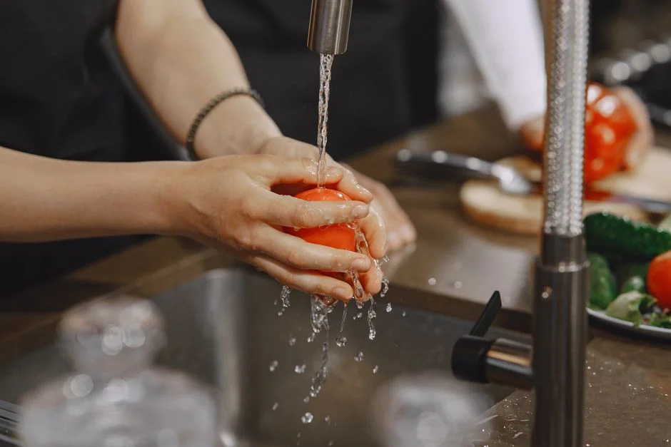 Close-up of gloved hands disinfecting a remote control with a cloth and spray bottle.
